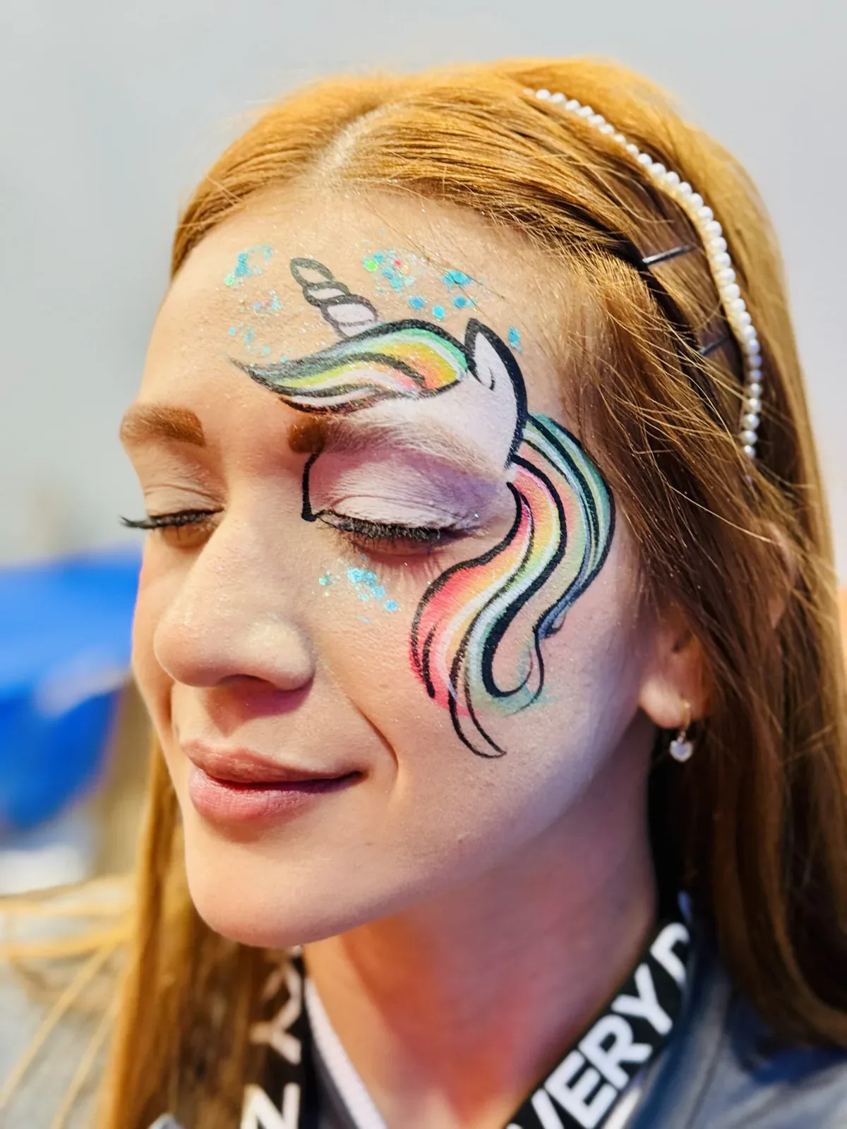 Adult with rainbow unicorn face painting from the Colory Faces portfolio.