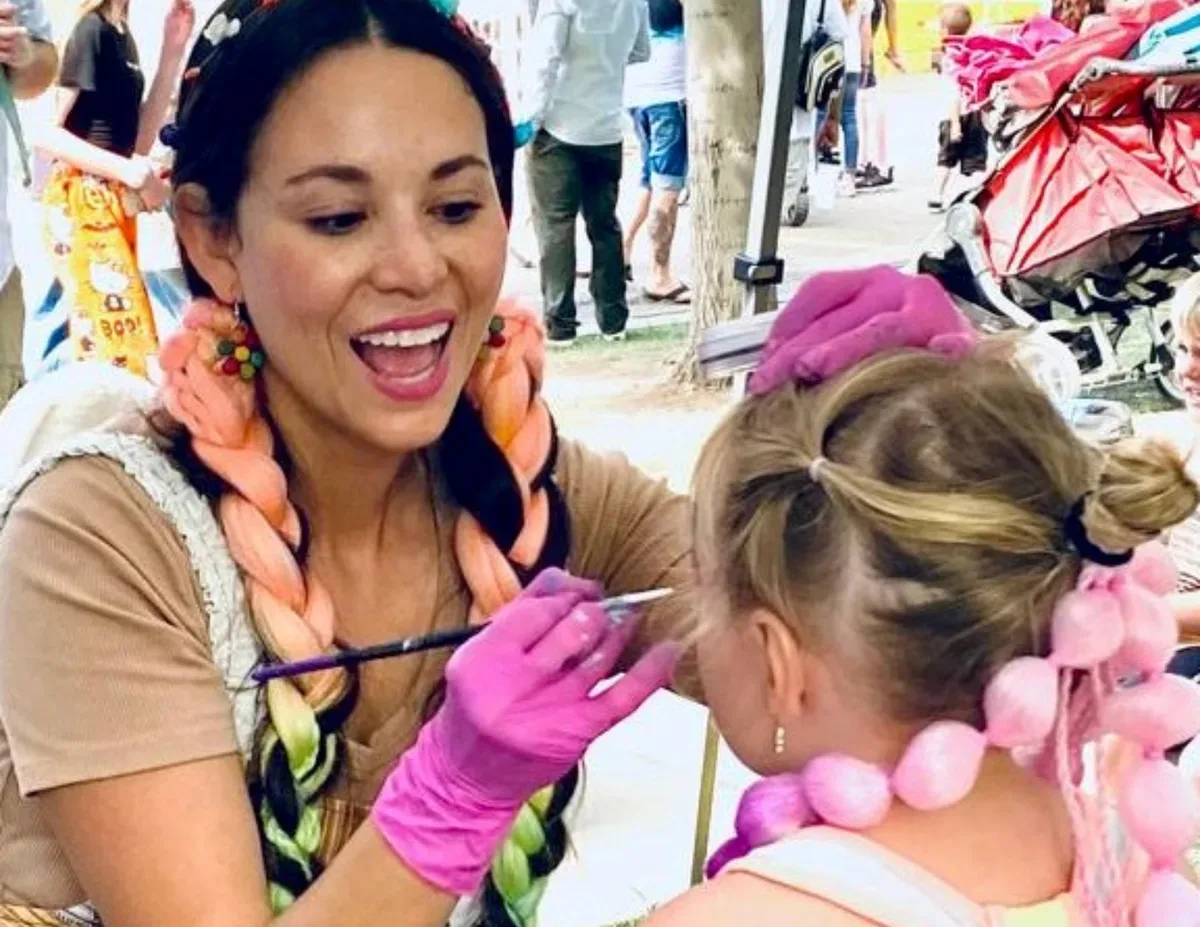 Colory Faces artist painting a child at an event.